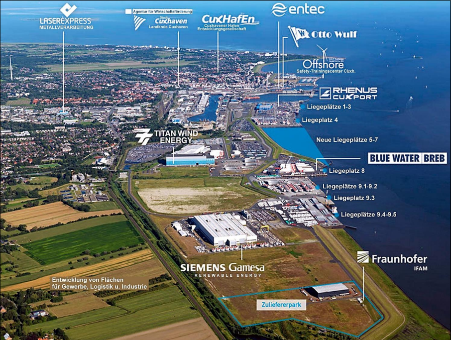 Luftaufnahme eines Hafen- und Industriegebiets an der Küste mit Hallen, Kaianlagen und beschrifteten Firmenstandorten.